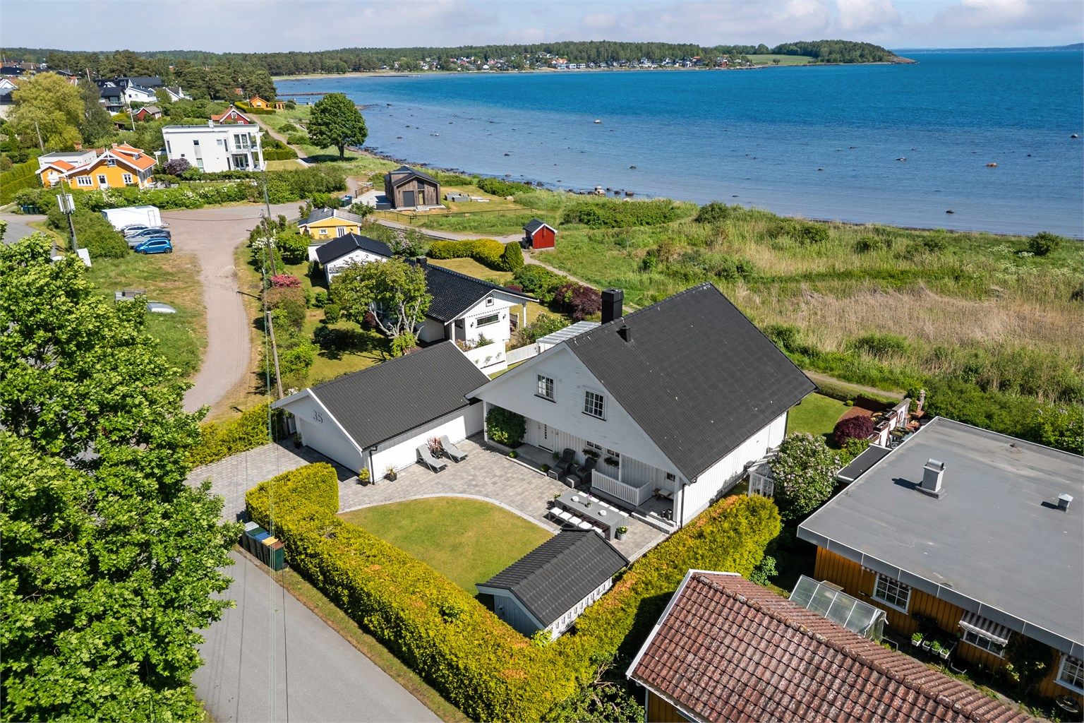 Hagen er pent opparbeidet med drivhus fra 2023, markterrasse og granittrapp som fører ned til kyststien og stranden.