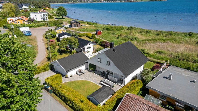 Hagen er pent opparbeidet med drivhus fra 2023, markterrasse og granittrapp som fører ned til kyststien og stranden.