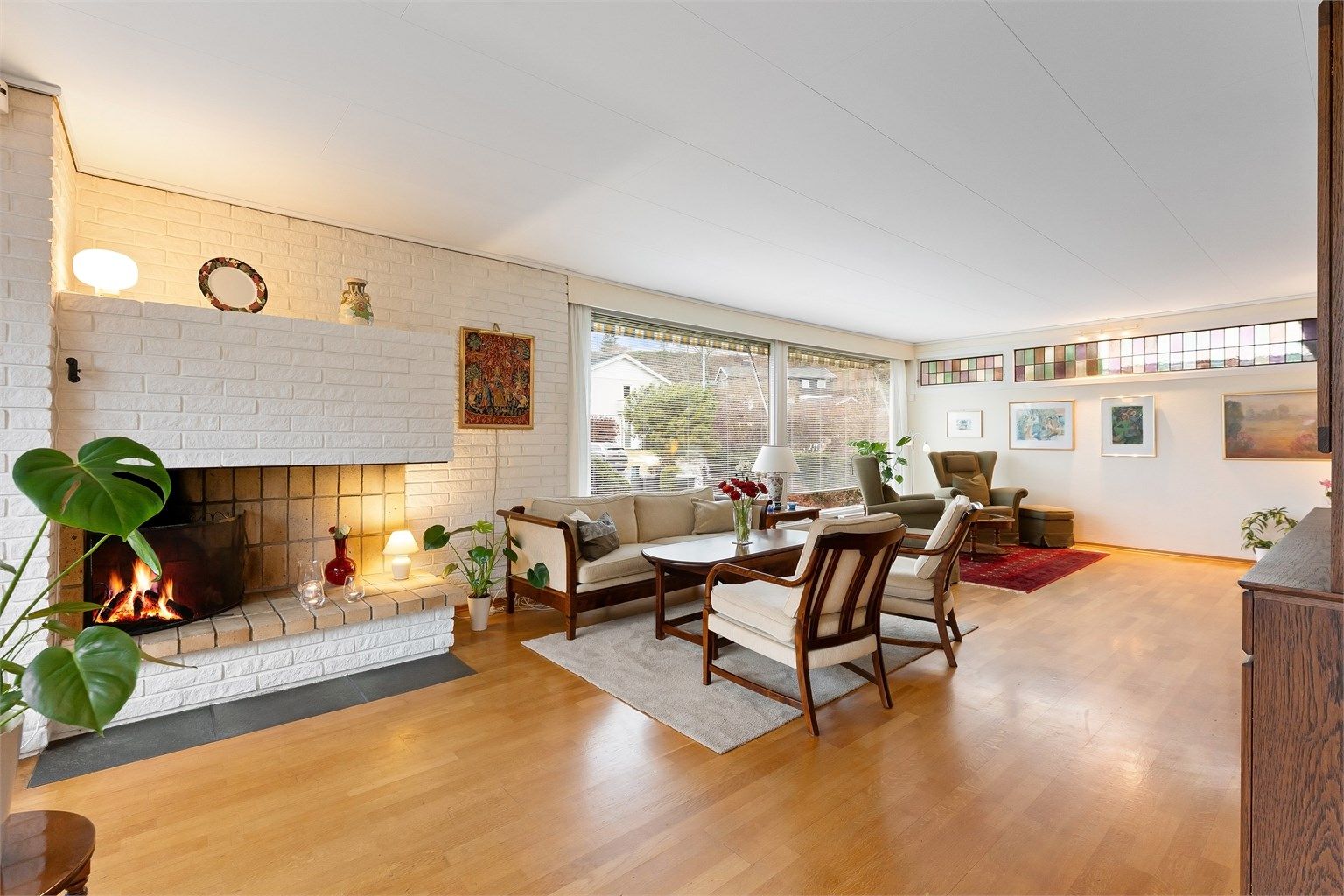 Den romslige stuen har parkett på gulvet og en sentral, åpen peis som et naturlig samlingspunkt.