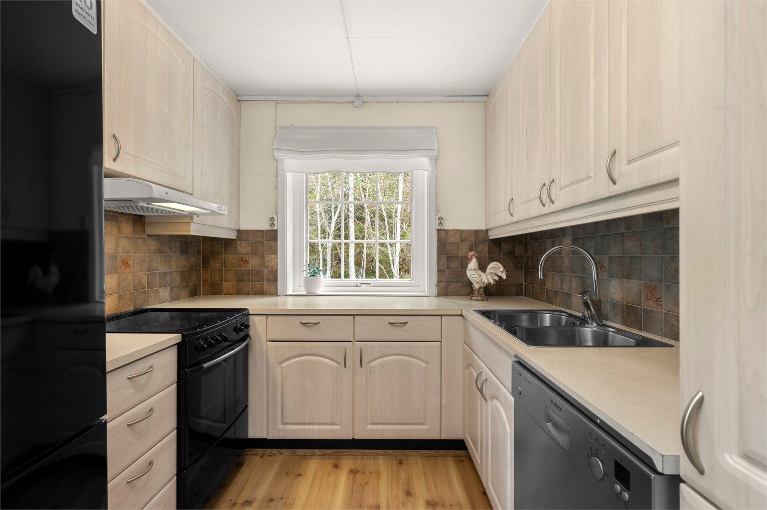 Funksjonelt kjøkken med lyse fronter, god arbeidsflyt og vindu som tilfører rommet behagelig dagslys.