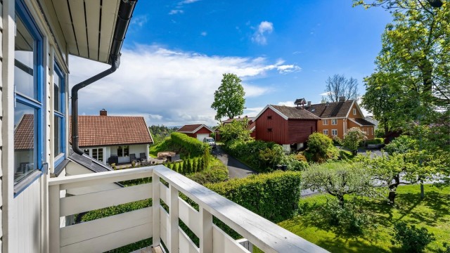 Utsyn mot et eldre stabbur og grønne omgivelser.