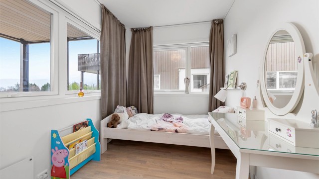 Et av de totalt fire soverommene i boligen, med god plass til seng og oppbevaring.