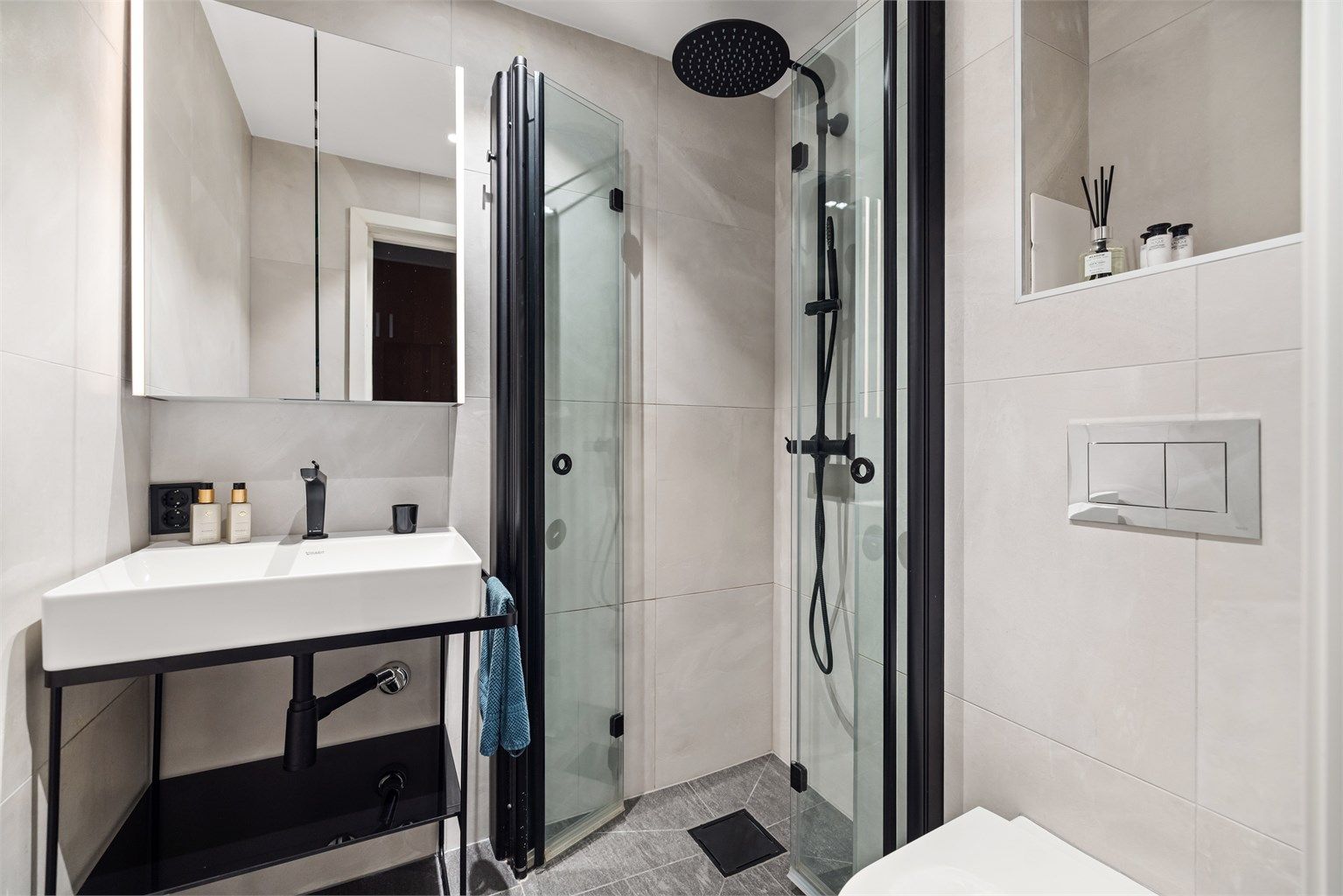 Badet er innredet med vegghengt toalett og egen dusjsone med innfellbare glassdører. Dusjen er tilkoblet både hånd- og regndusj.