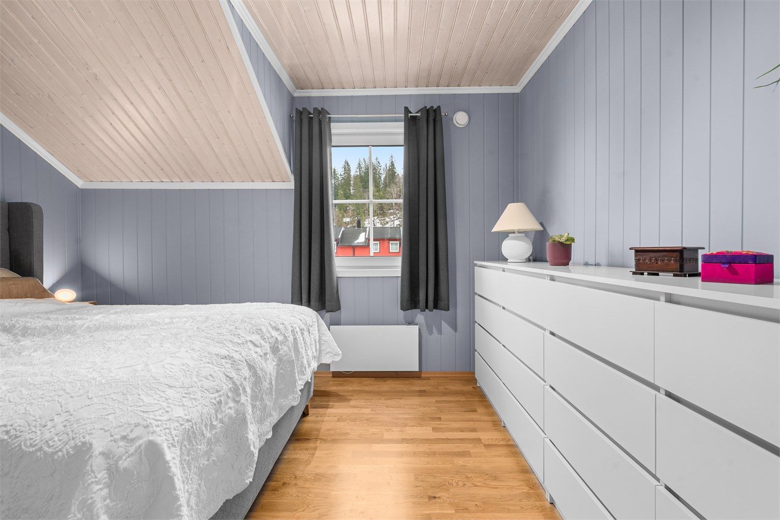 Rommet har en lun atmosfære med panel på veggene og skråtak.