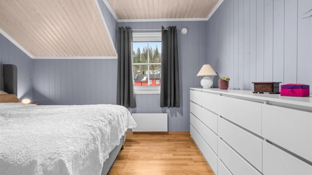 Rommet har en lun atmosfære med panel på veggene og skråtak.