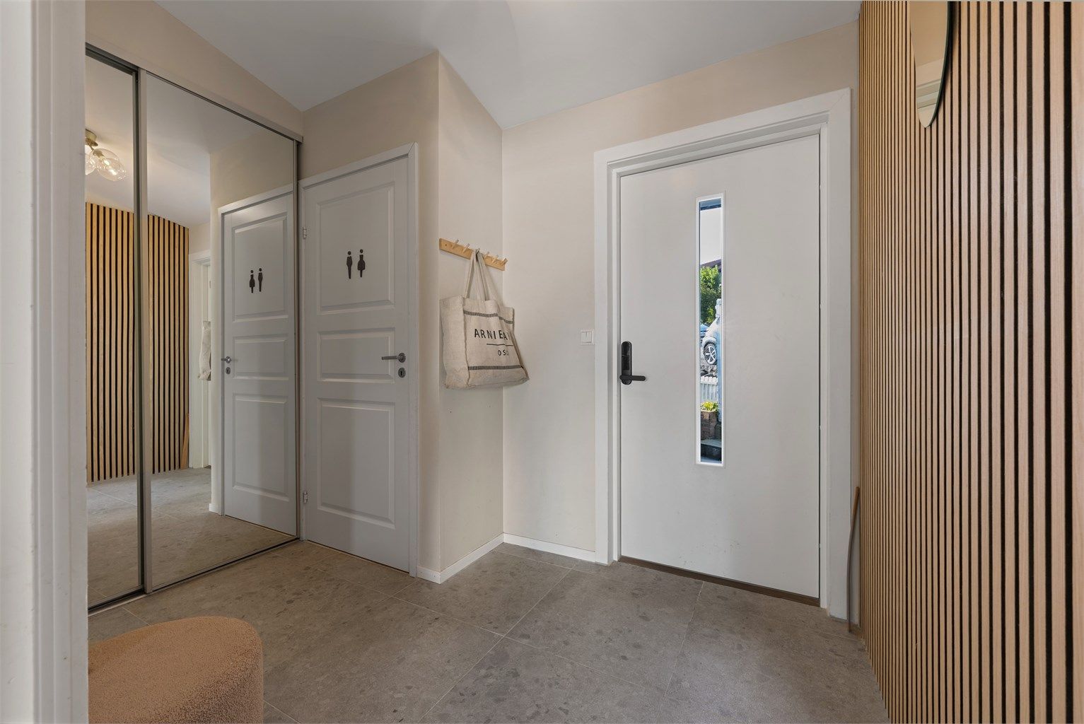 Entré med plass til å henge av yttertøy i skyvedørsgarderobe med speilfronter . Fine fliser på gulv. 