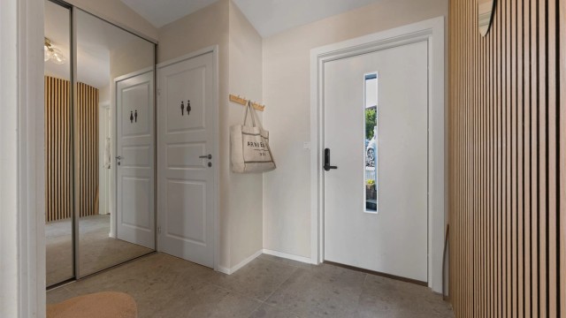 Entré med plass til å henge av yttertøy i skyvedørsgarderobe med speilfronter . Fine fliser på gulv.