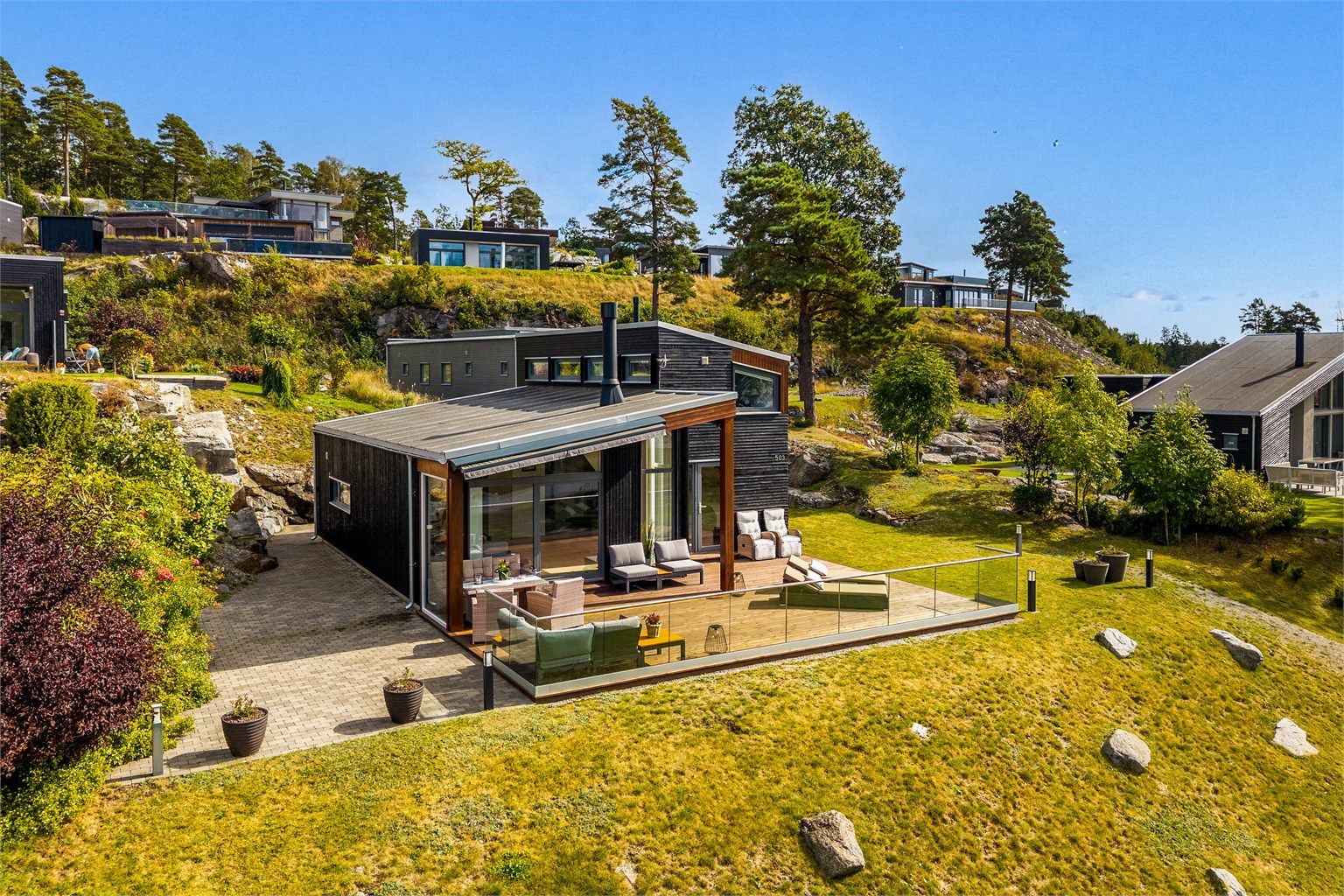 MOT SJØEN: Hagen er variert og flott beplantet med terrasse og platting.