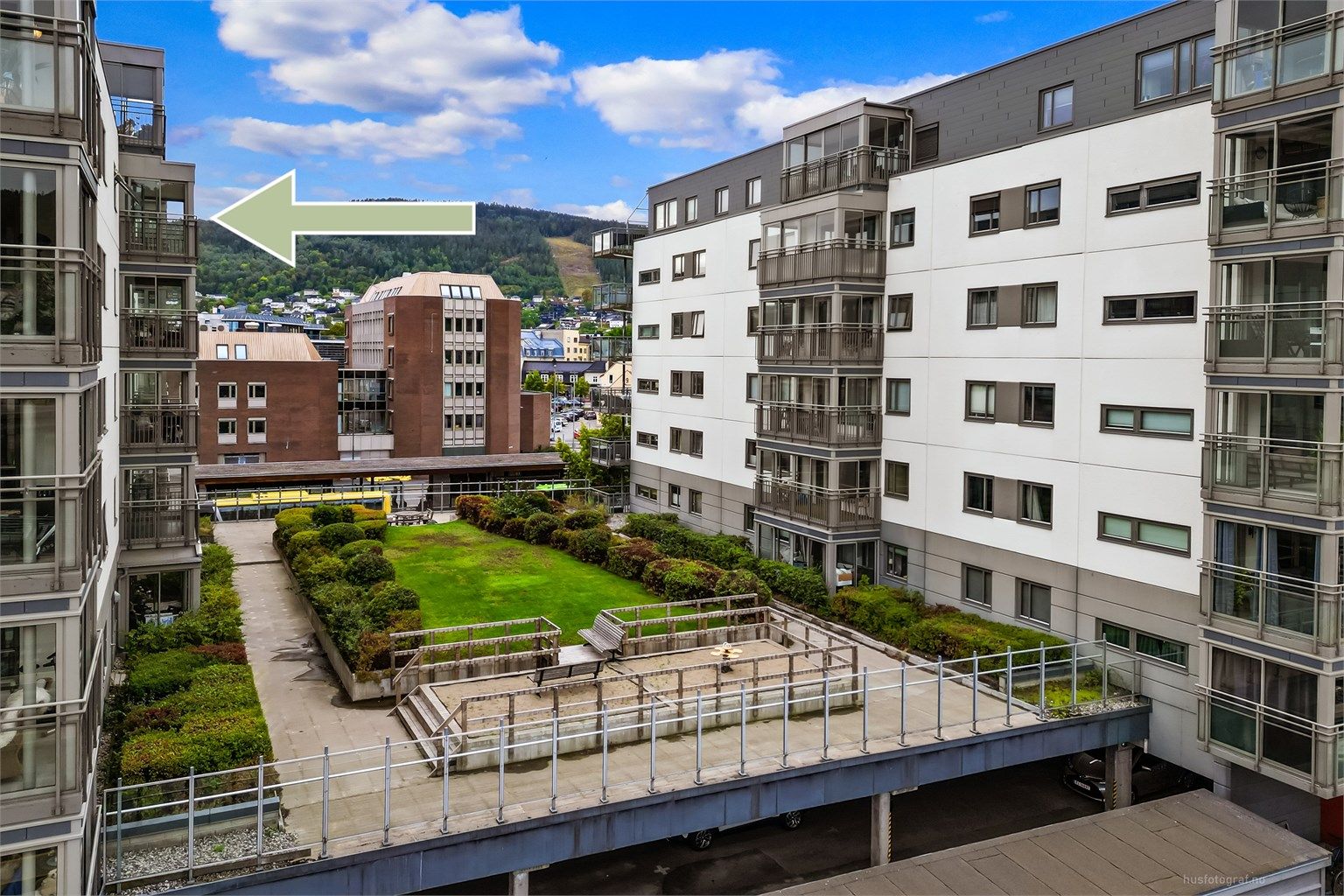 Pent opparbeidet felles atrium mellom bygningene med grøntareal og sitteplasser.