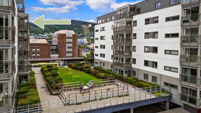 Pent opparbeidet felles atrium mellom bygningene med grøntareal og sitteplasser.