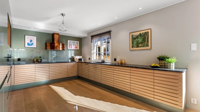 Moderne JKE-kjøkken fra 2020 med benkeplate av stein. Kjøkkenet har god plass til mange, og er i åpen løsning med spisestuen