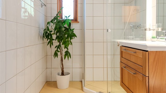 Baderom med flislagte overflater, gulvvarme og dusjhjørne med glassdører.