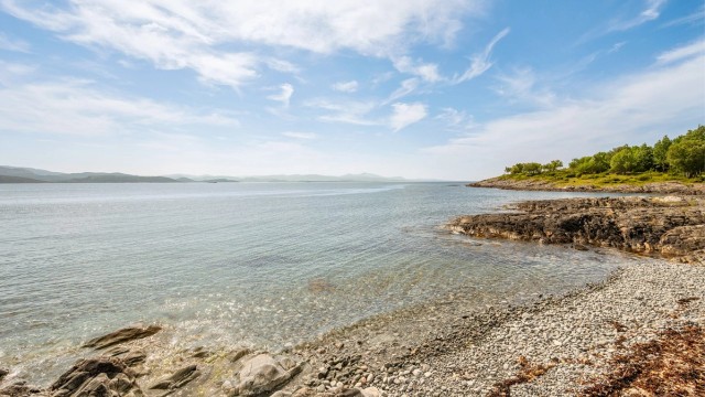 Meget pent opparbeidet naturtomt som ligger skjermet til fra naboene. Egen strandlinje med rullesteiner.
