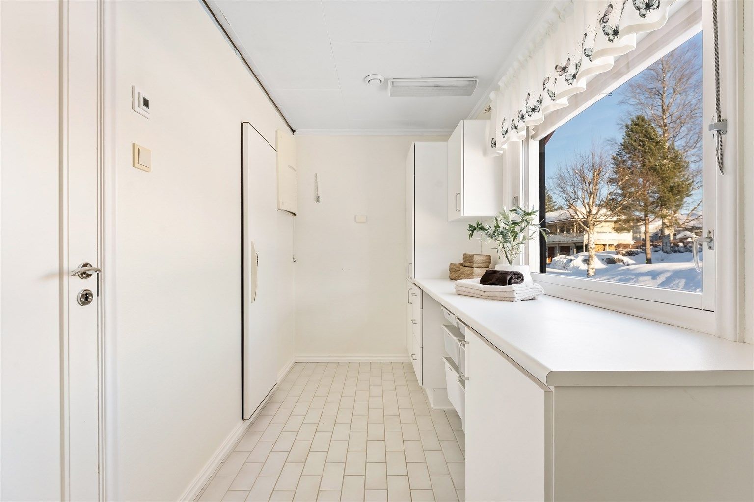 Separat og praktisk vaskerom med flislagt gulv og gulvvarme.