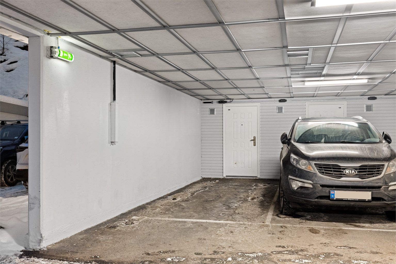 Medfølgende parkeringsplass med bod i bakkant. 