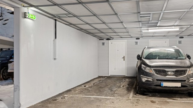 Medfølgende parkeringsplass med bod i bakkant.