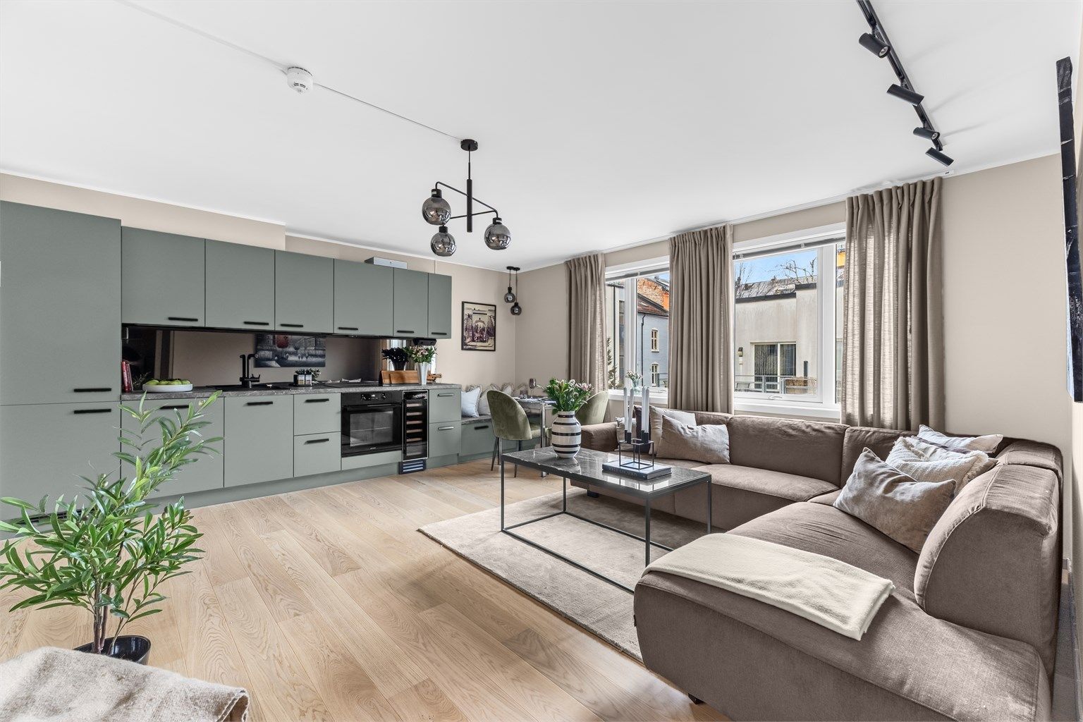 Leilighetens åpne stue- og kjøkkenløsning skaper en lun og sosial atmosfære.