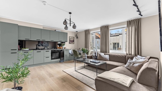 Leilighetens åpne stue- og kjøkkenløsning skaper en lun og sosial atmosfære.