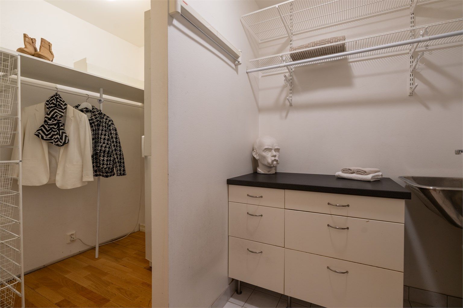 Praktisk vaskerom med opplegg og god plass til vaskemaskin og tørketrommel. Rommet har frittstående skap med ovenpåliggende benkeplate i laminat og vegghengt utslagsvask.