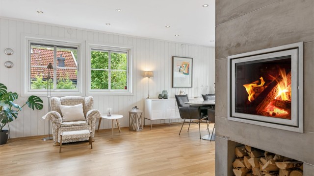 Peisen er strategisk plassert midt i rommet og bidrar med varme og atmosfære til både spiseområdet og stuen.