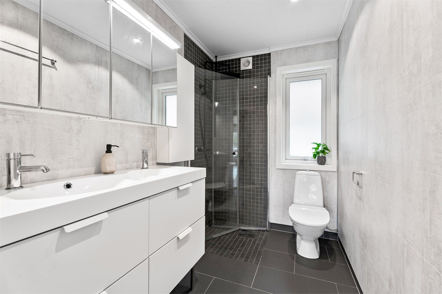 Baderommet har fliser på gulv og i dusjsonen samt baderomsplater på vegg. Det er varmekabler i gulvet. 