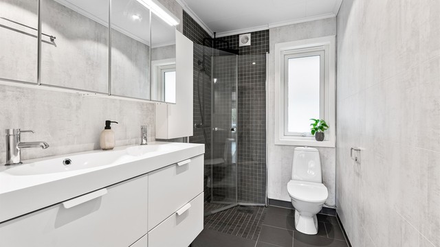 Baderommet har fliser på gulv og i dusjsonen samt baderomsplater på vegg. Det er varmekabler i gulvet.