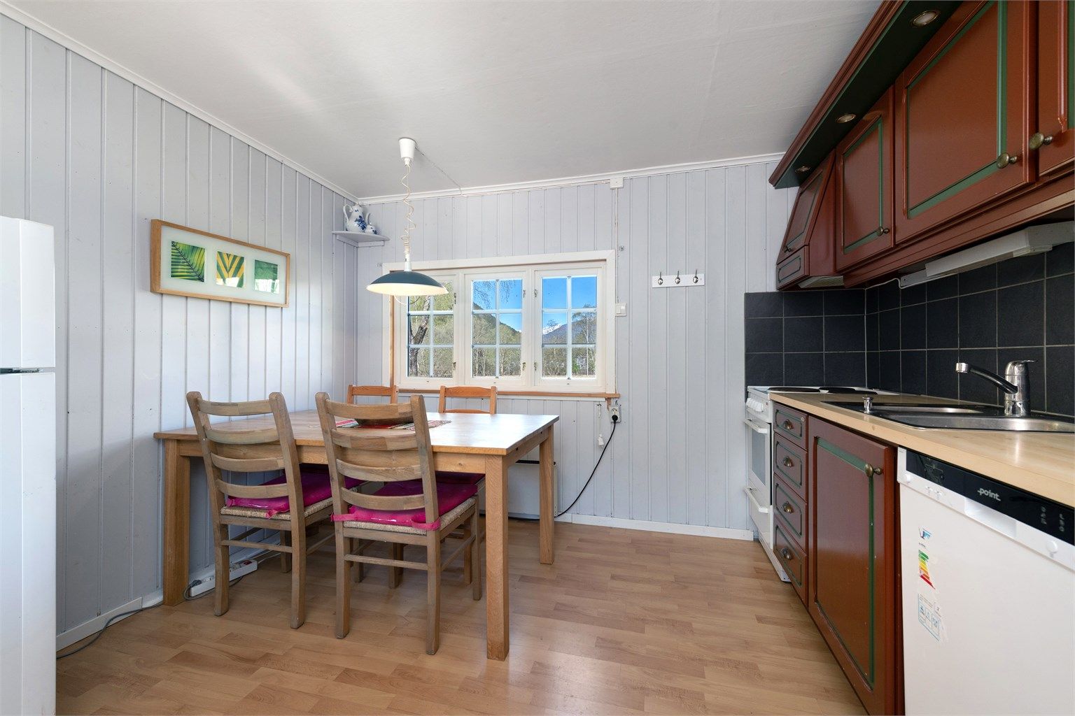 Her er det plass til et spisebord, og kjøkkenet er utstyrt med komfyr og oppvaskmaskin.