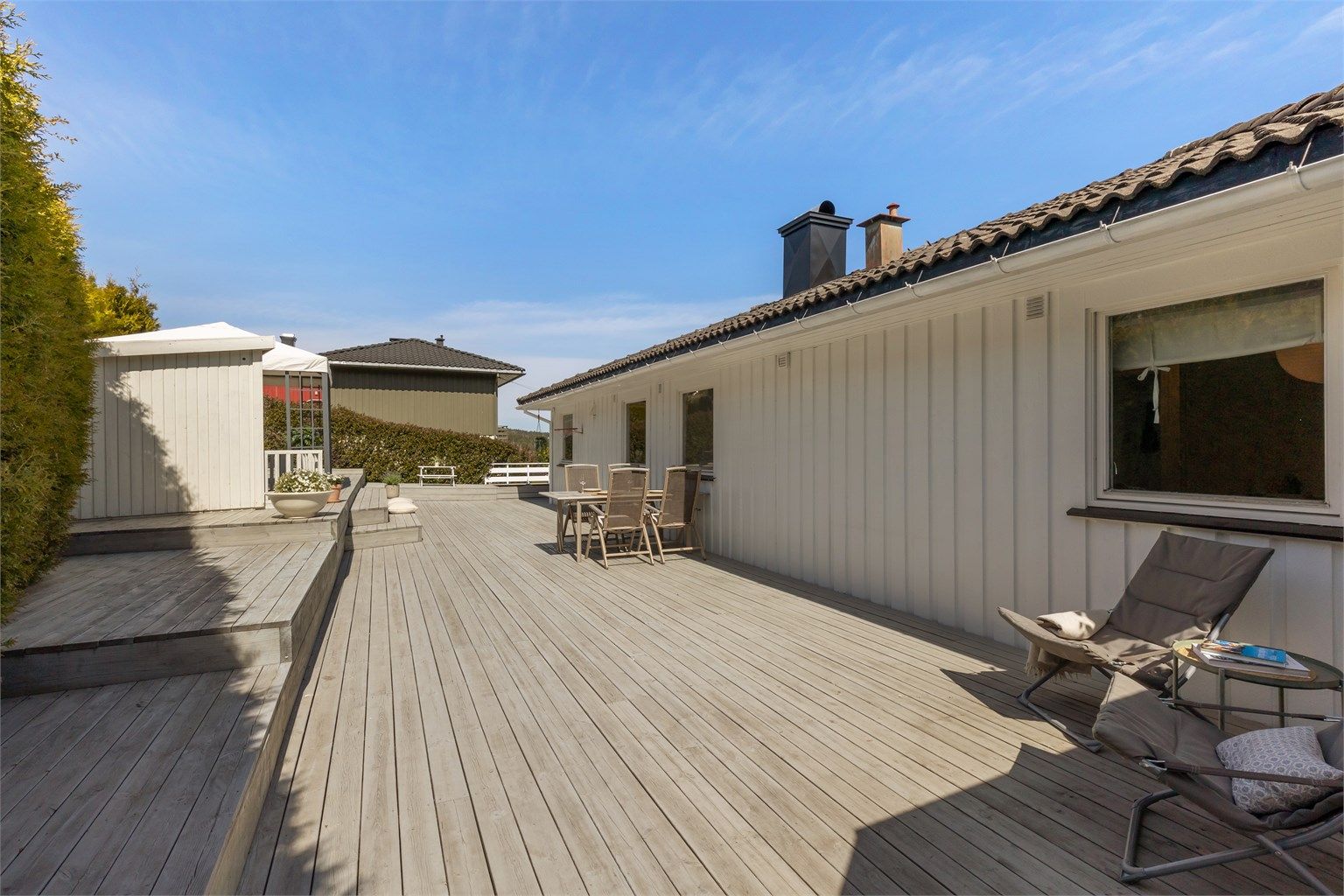 Terrassen strekker seg rundt hushjørnet og bort til en overbygget del ut for stua
