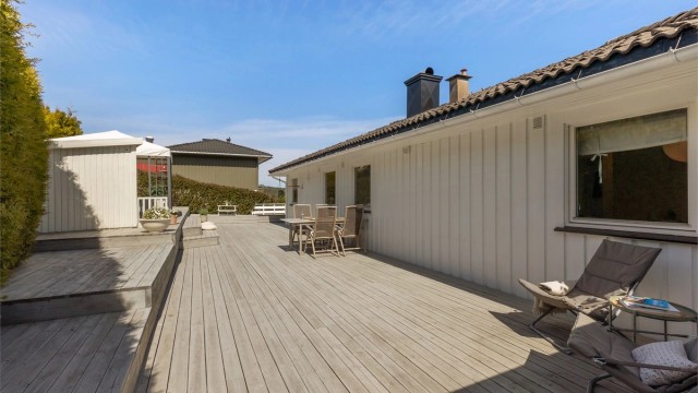 Terrassen strekker seg rundt hushjørnet og bort til en overbygget del ut for stua