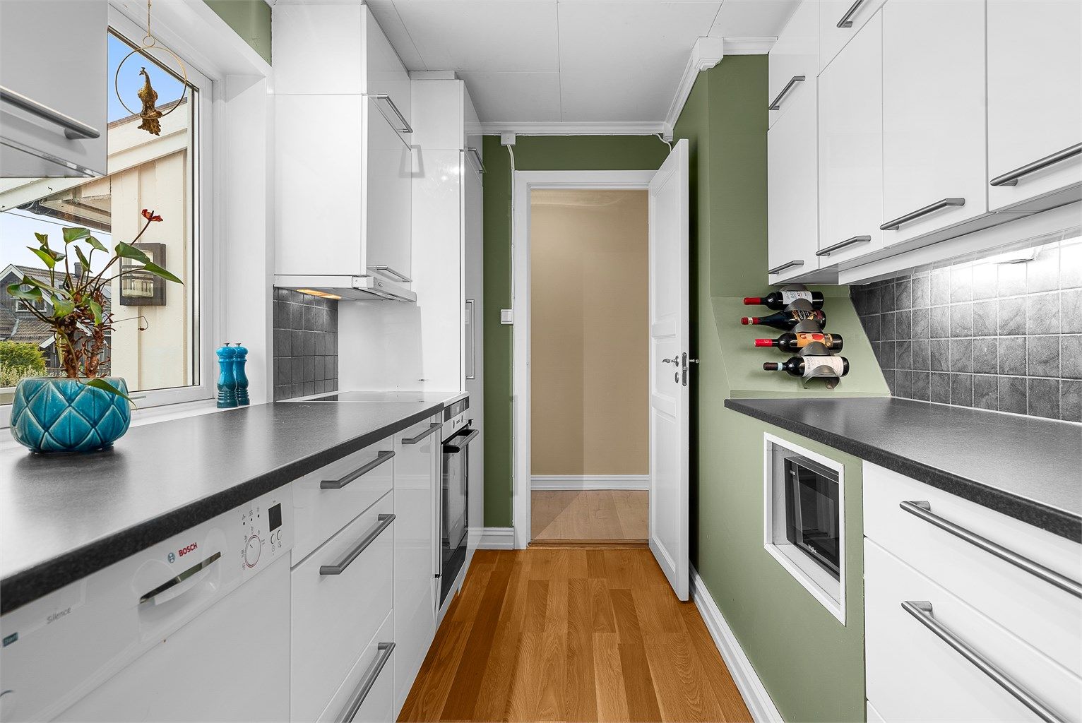 Kjøkkeninnredning fra 2011. Gulvflate belagt med laminat. Veggflater med malte flater. Himlingsflate med hvite himlingsplater. Kjøkken med høyglans fronter. Benkeplater av laminat.