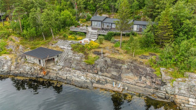 Dronebildet viser den flotte sammenhengen mellom hytta, de store terrassearealene, naustet og sjøen.