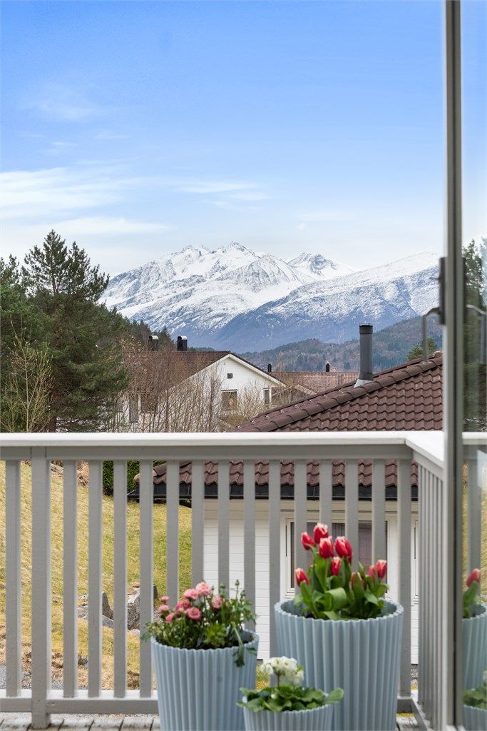 Utsikten fra balkongen strekker seg mot de snøkledde fjelltoppene.
