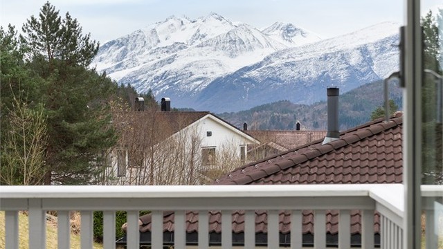 Utsikten fra balkongen strekker seg mot de snøkledde fjelltoppene.