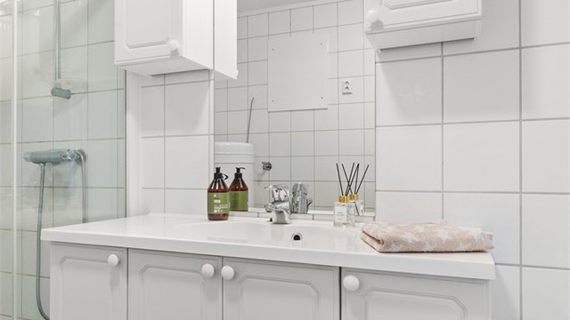 Badet har vegghengt servantinnredning, speil med overlys og stikkontakt.