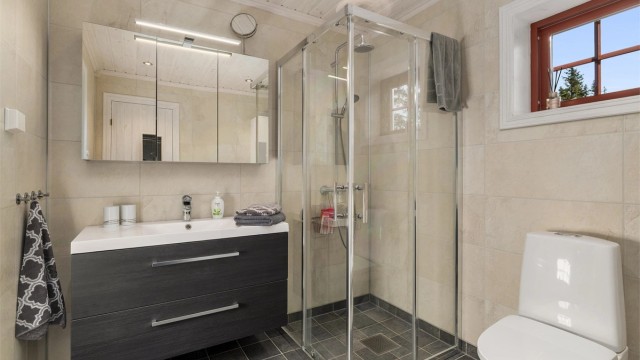 Badet i tilbygget har en mer moderne standard med lyse flater og badstue.