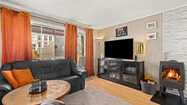 Stuen har en peisovn med glassdør som gir god varme og en hyggelig atmosfære.