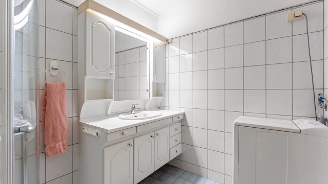 Baderomsinnredning med servant, speilskap og godt med oppbevaringsplass.