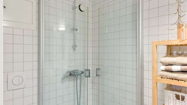 Badet er utstyrt med dusjhjørne med glassdører og vegghengt toalett.