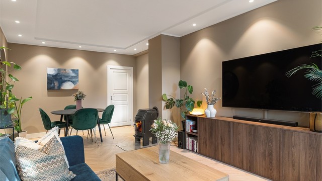 Peisovnen med glassdør er sentralt plassert mellom sittegruppen og spiseplassen, slik at hele rommet nyter godt av varmen og det levende flammespillet.