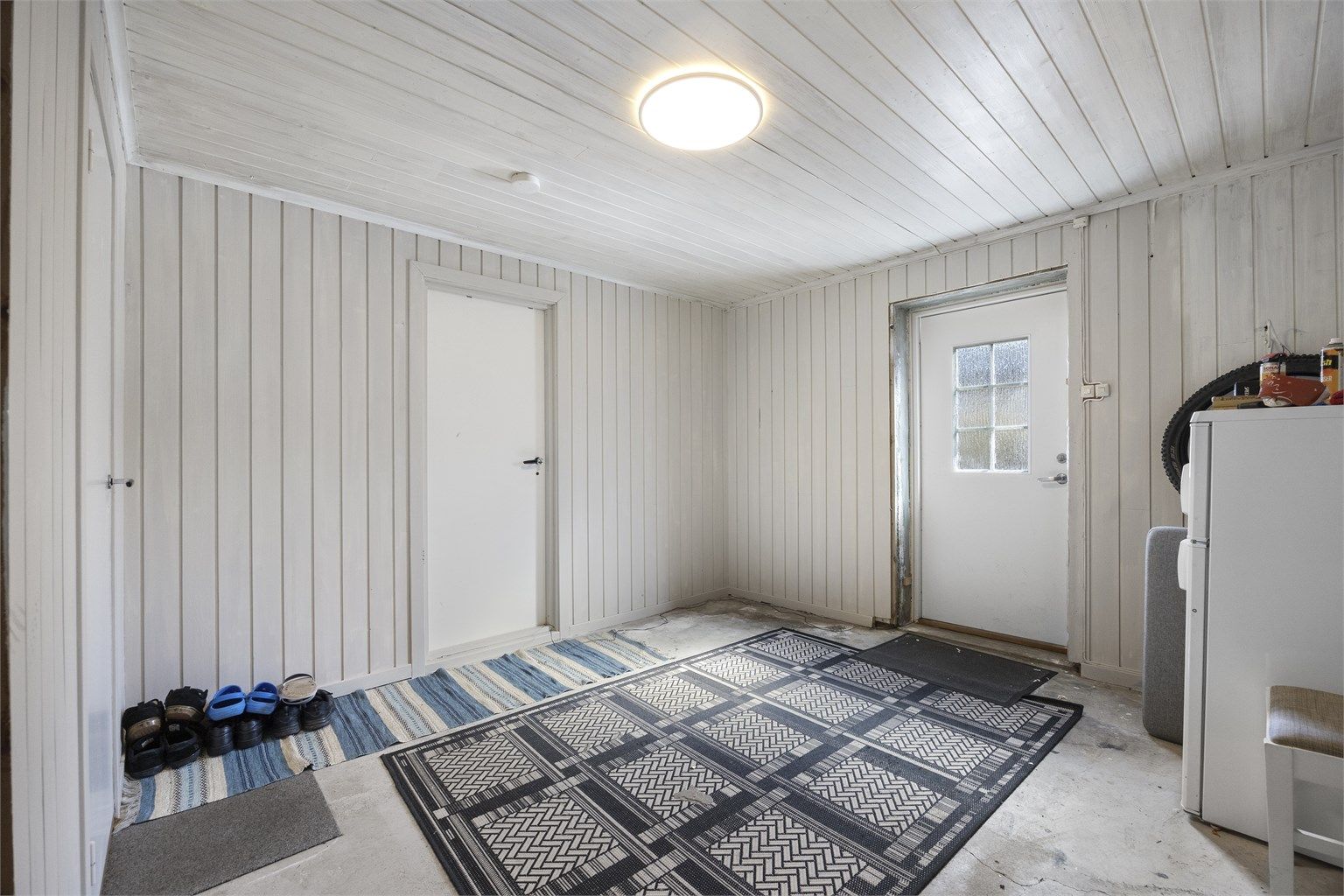 Inngangsparti i underetasjen med panel på vegger og adkomst til de øvrige rommene.