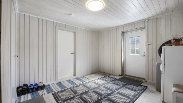 Inngangsparti i underetasjen med panel på vegger og adkomst til de øvrige rommene.