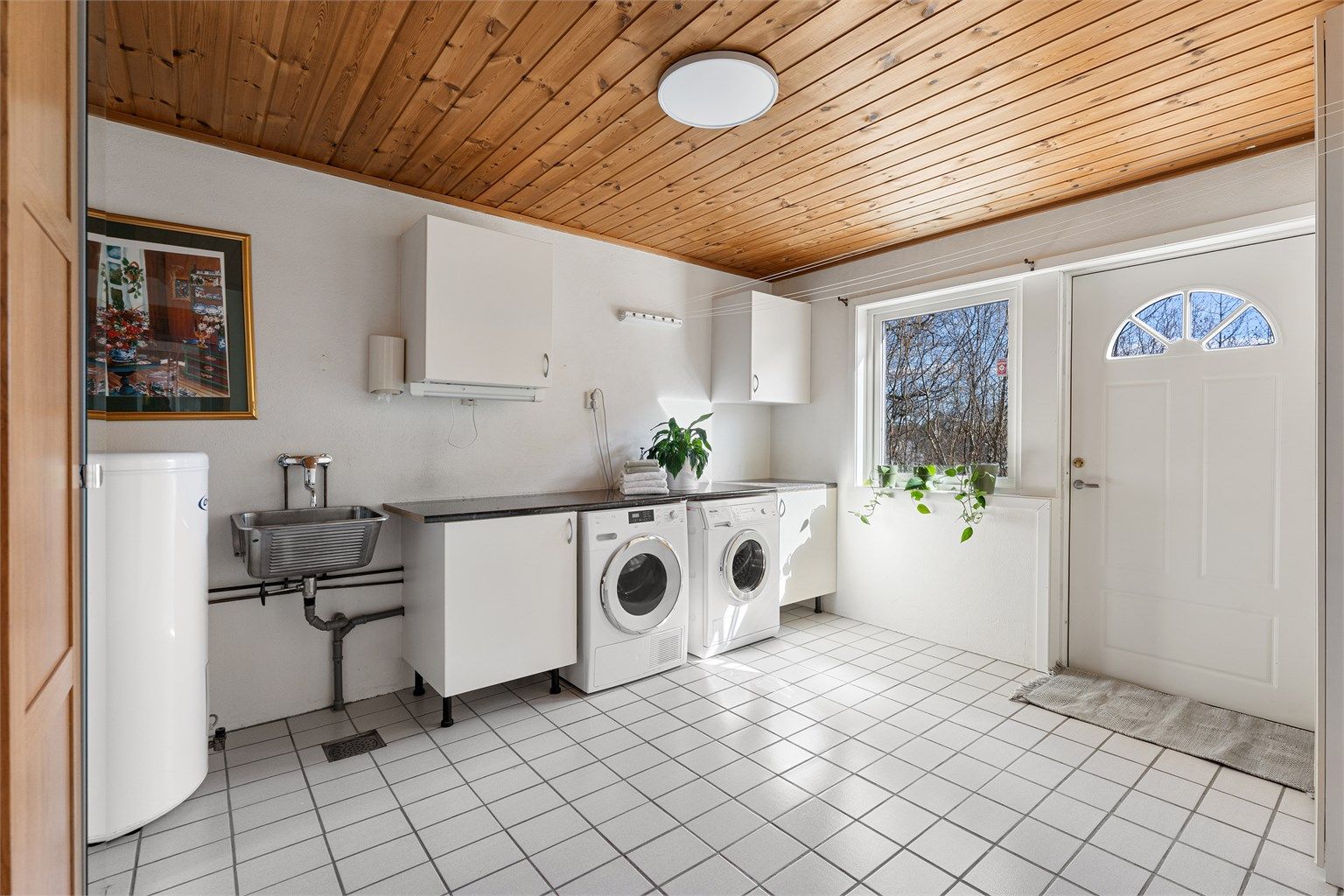 Praktisk vaskerom i underetasjen med egen inngang, flislagt gulv med varme og opplegg for vaskemaskin.