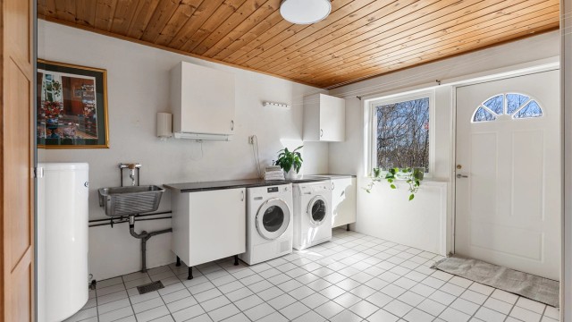 Praktisk vaskerom i underetasjen med egen inngang, flislagt gulv med varme og opplegg for vaskemaskin.
