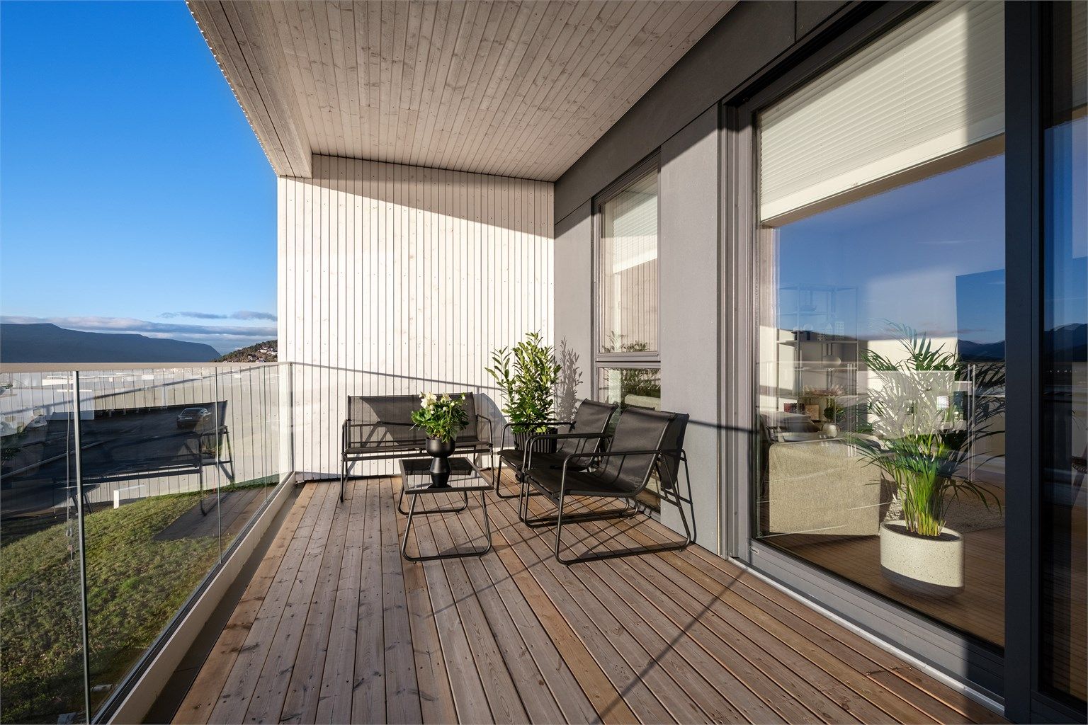 Skjermet overbygd balkong med glassrekkverk mot syd