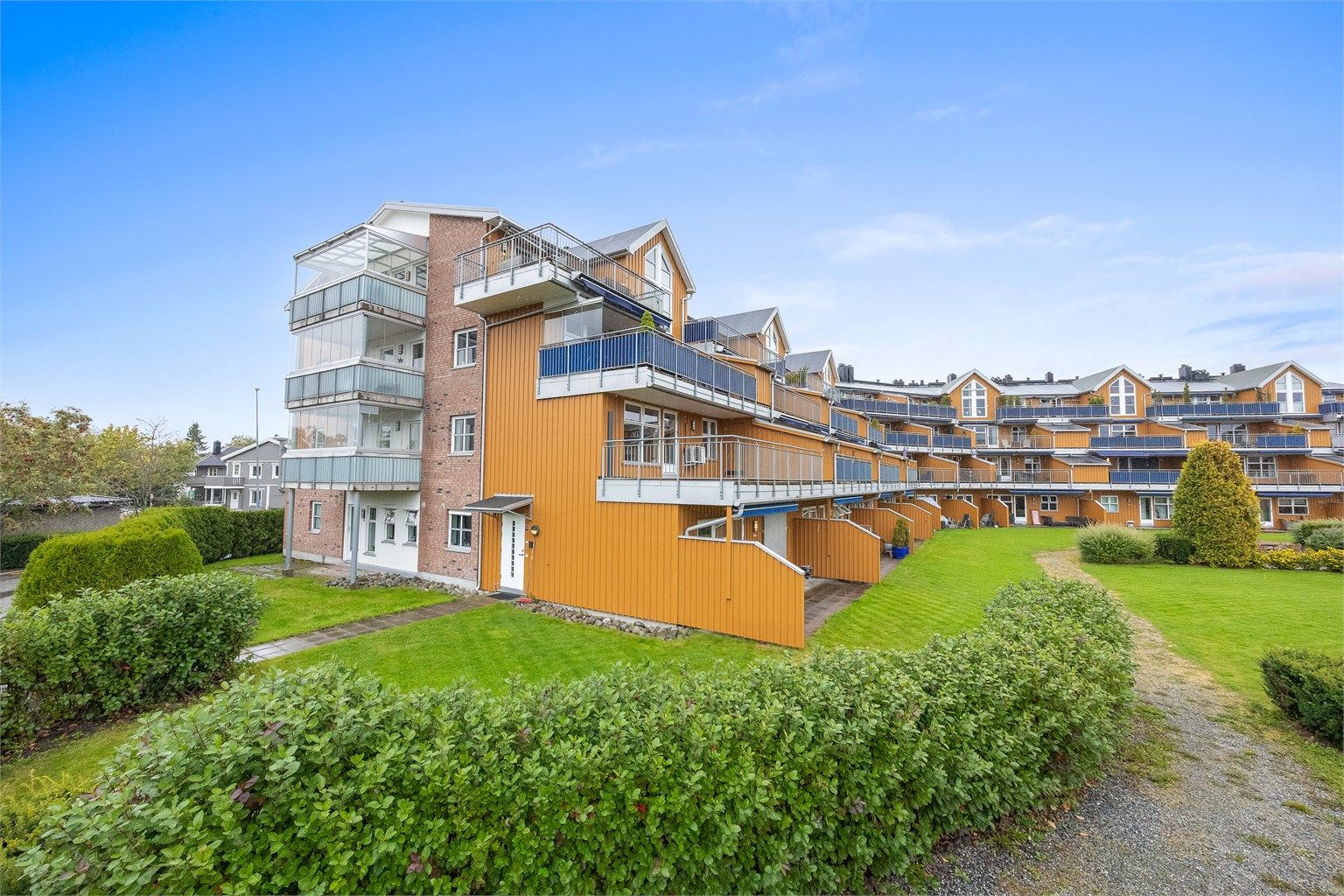 Terrassert leilighetsbygg med felles parkanlegg og grønne plenarealer.