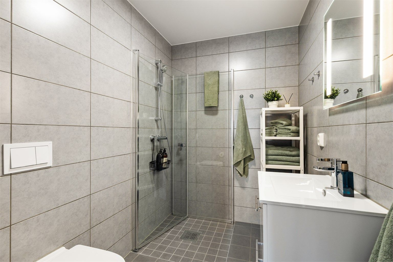 Bad i hovedetasjen med flislagt gulv med gulvvarme, vegghengt toalett og dusjhjørne med inn- og utadslående dører.