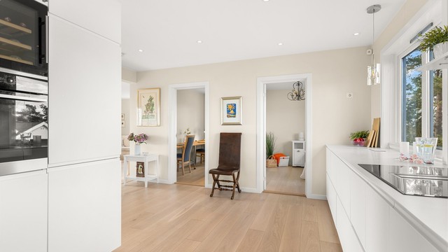 Den delvis åpne løsningen mellom kjøkken og stue skaper en sosial og luftig atmosfære.