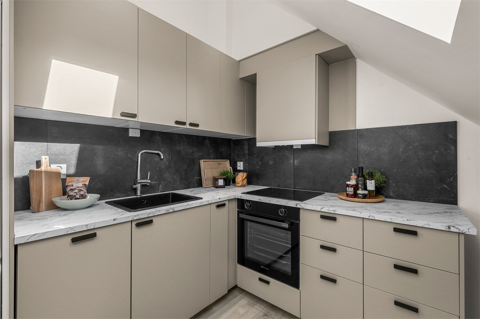 Kjøkkenet er tidsriktig innredet med lune fargevalg og integrert stekeovn, platetopp, oppvaskmaskin og kjøleskap med fryser.