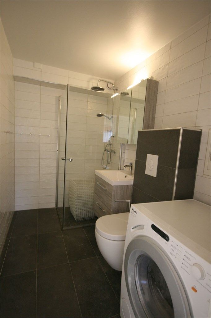 Nyere flislagt baderom med vaskemaskin.