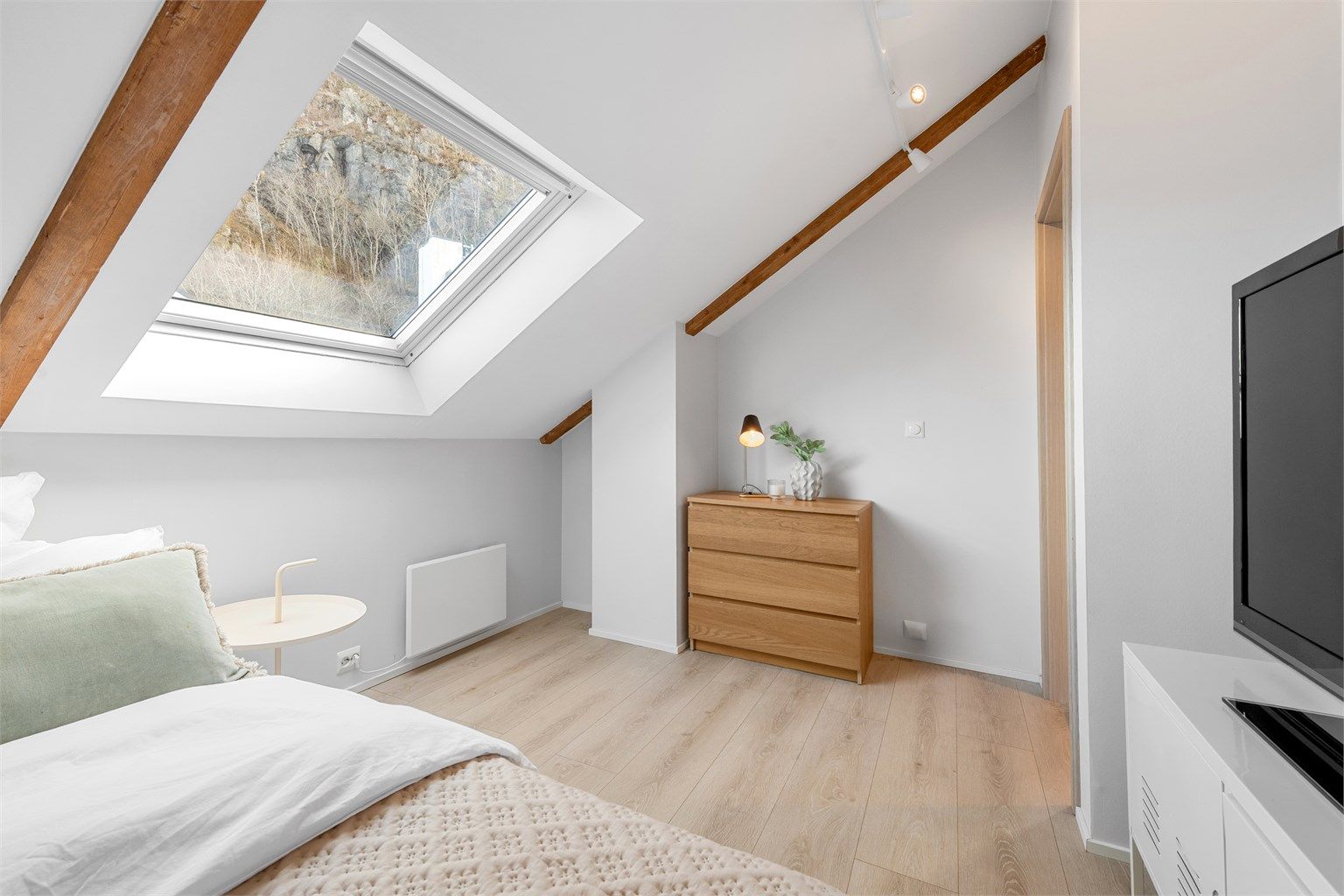 Soverommet har malte flater og laminat på gulvet, i tråd med resten av leiligheten.